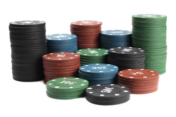 Stacks of poker chips of four denominations are isolated on a white background. Selective focus