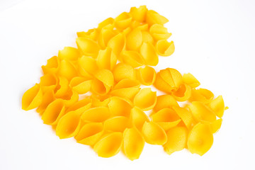 Heart of yellow dry Italian pasta konkiloni closeup on white background.