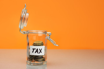 tax word on piggy Bank, moneybox, money jar with coins