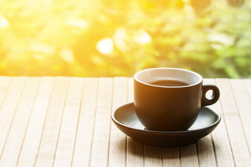 A cup of coffee on wooden table cloth in the open air with sunlight flash effect