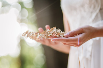 Bride is holding a diadem. Beautiful light, blurred background.
