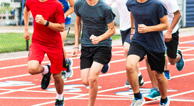 Boys run training together in a group on a red track