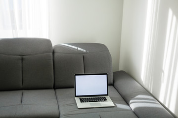 Open laptop on the couch. Modern comfortable workplace, distance work. Empty place for text, copy space.
