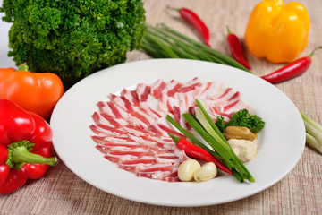 Plate with meat cutting, strips of bacon and sliced lard, sauce, greens. The concept of Russian Ukrainian restaurant.