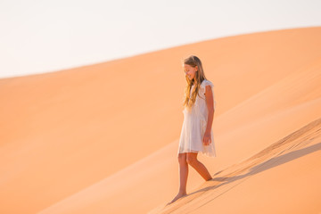 Fototapeta na wymiar Girl among dunes in desert in United Arab Emirates