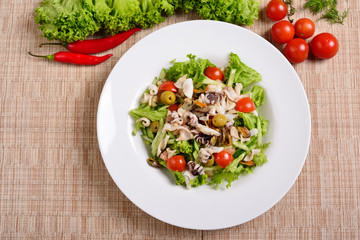 Salad with grilled octopus, potatoes, arugula, tomatoes and olives. Top view
