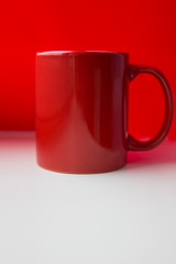 Red ceramic mug on a white and red background.