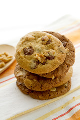 Fresh homemade gourmet cookies pile, chocolate flavour, with nuts and almonds, natural looking, resting on napkin, white clear background for breakfast, dessert, recipe