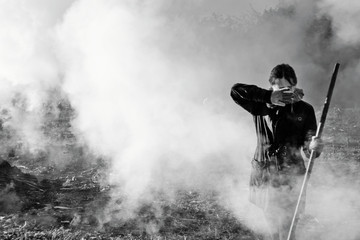 Woman covers face in smoke. Work in garden. Black white photo