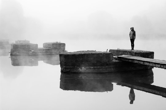Girl in morning fog. River in mist. Black white photo