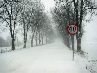 Road sign on a side of a road covered with snow