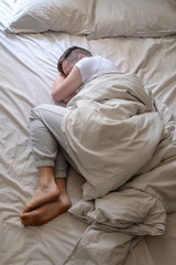 Obraz premium Young caucasian man sleeping in his bed