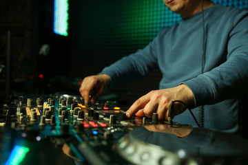 dj's hand is mixing tracks at party in night club. disc jockey playing music on the modern...