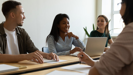 Young happy african american businesswoman laugh using laptop at briefing break. Relaxing diverse woman mentor enjoying joke with colleagues. Black female manager funny at meeting.