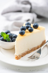 Slice of cheesecake topped with blueberries on a white plate. Tasty classical new york style cheesecake