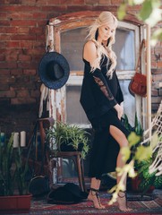 Portrait of beautiful young blonde in the black clothing of style of бохо in a summer arbour