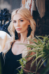 Fototapeta na wymiar Portrait of beautiful young blonde in the black clothing of style of бохо in a summer arbour