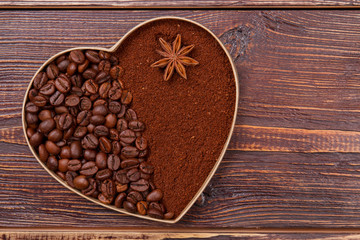 Heart made of coffee beans and instant coffee. Anise on the brown instant coffee. Brown wooden background.