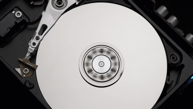 Macro, Close-Up of Computer Hard Disk Drive Spinning and Writing then Rotation Stop. Blue Lights Blinking. Slow Motion. 