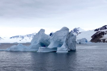 Fototapeta na wymiar Iceberg in antarctic ocean with mountain, stormy sky, Antarctica
