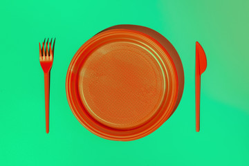 Plastic disposable tableware, plate, knife and spoon on mint background