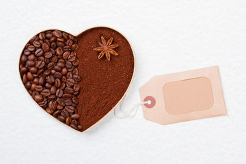 Heart made of instant powder coffee and beans. Blank paper tag. Isolated on white background.