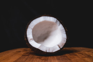 Split coconut is lying on a wooden Board. Tasty tropical fruit. healthy nutrition. Diet concept. Concept design. Closeup of coconut. Healthy fresh nutrition. Vegetarian healthy food. Dark background.
