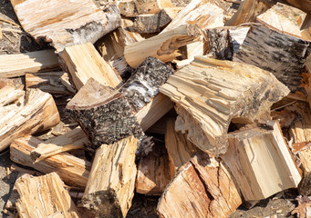 Pile of chopped birch wood is lying on ground. Natural background. Pile of split birch firewood
