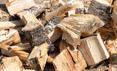 Pile of chopped birch wood is lying on ground. Natural background. Pile of split birch firewood