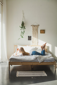 portrait of a beautiful young blonde girl in a white shirt lying on the bed