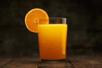 Fresh orange juice and fruit on a wooden table - natural and healthy food and drink. One glass of cocktail with a slice of fruit