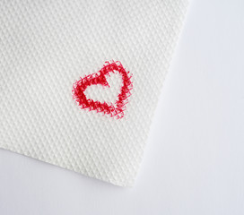 painted heart with red lipstick on a white paper napkin