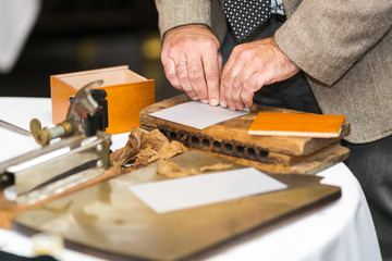 Men's hands twist Cuban cigars using traditional methods and equipmentby hand.