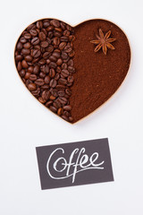 Decorative coffee heart isolated on white. Coffee beans and instant coffee powder with anise.