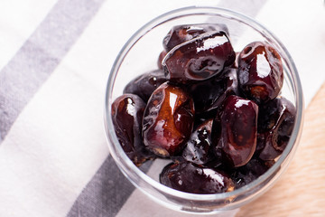 Bowl of dates and a linen napkin on a wooden background.