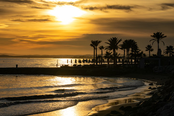 a golden beach scene of a sunset setting in Marbella, Spain 