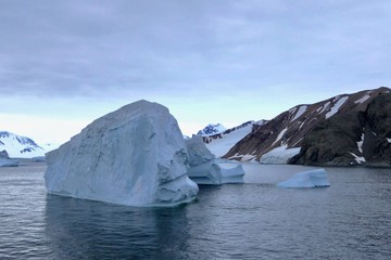 Fototapeta na wymiar Iceberg in antarctic ocean with mountain, stormy sky, Antarctica