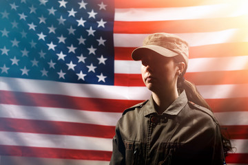 Memorial Day, Independence Day. Portrait of A female soldier in uniform, against the background of the American flag. The concept of the American national holidays and patriotism