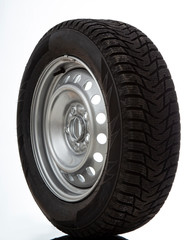 Car wheel and winter studded tire on white