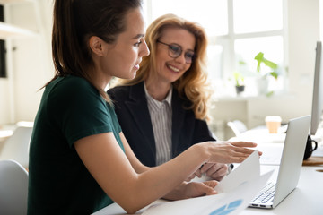 Young businesswoman presentation project using laptop for mature female mentor in boardroom at...