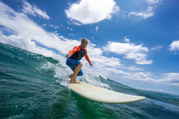 muscular surfer with long white hair riding on big waves on the Indian Ocean island of Mauritius