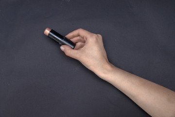 Naklejka premium Highlighter for sculpting in a woman's hand on a black background. Advertising.Decorative cosmetics for makeup. Space for text. Rouge.