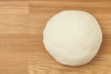 Raw dough for bread or pizza on a wooden background. Top view