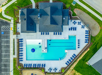 Aerial top down view of new construction American residential community clubhouse pool with beach chairs at a new development