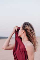 portrait of a young slender girl in a red dress in the wind in the desert