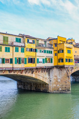 Fototapeta na wymiar Famous Ponte Vecchio Bridge, medieval stone bridge over the Arno River in Florence, Tuscany, Italy. Major landmark of the Italian city. Colorful houses on the construction. Vertical photo