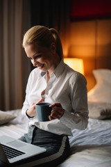 Businesswoman relaxing in hotel room. Young beautiful woman drinking coffee.	