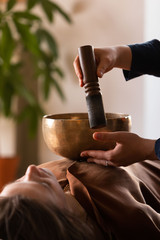 Woman making relaxing massage, meditation, sound therapy with tibetian singing bowls. Stress...