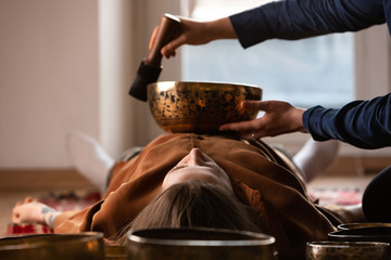 Woman making relaxing massage, meditation, sound therapy with tibetian singing bowls. Stress...