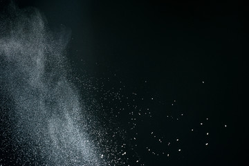 Wonderful pattern of white powder of light snow and flour explodes on black background